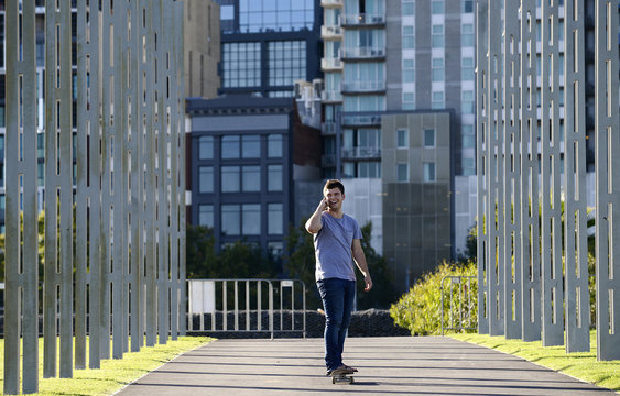 Young man on skateboard, using mobile phone