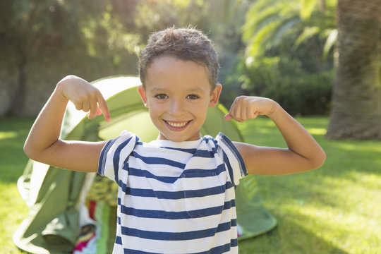 Portrait of boy in garden flexing muscles