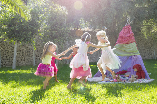 Five girls in fairy costume playing in garden