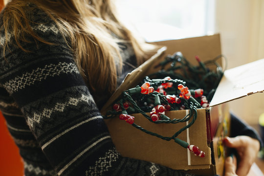 Woman carrying Christmas lights in cardboard box
