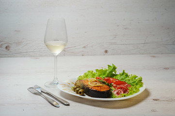 Grilled salmon and whtie wine on wooden table.