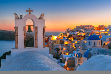 Arch with a bell, white houses and church with blue domes in Oia or Ia at sunset, island Santorini, Greece  - obrazy, fototapety, plakaty