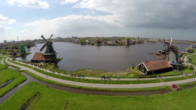 Aerial Zaanse Schans moving past windmills then turning towards mills blades turning by wind sustainable clean energy great tourist attraction Netherlands near Amsterdam drone footage bird-eye view 4k