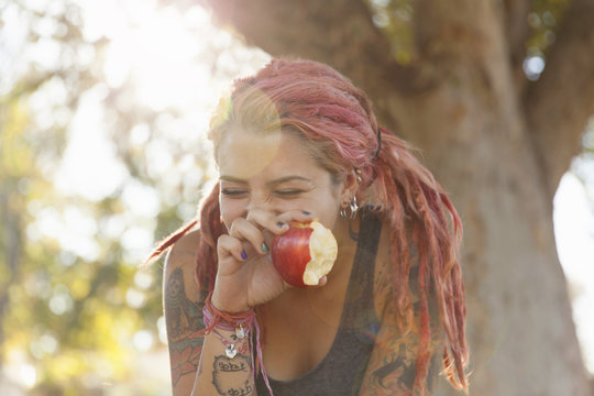 Young woman with dreadlocks eating apple 