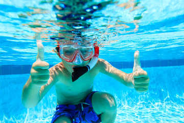 happy little boy swimming underwater with thumbs up