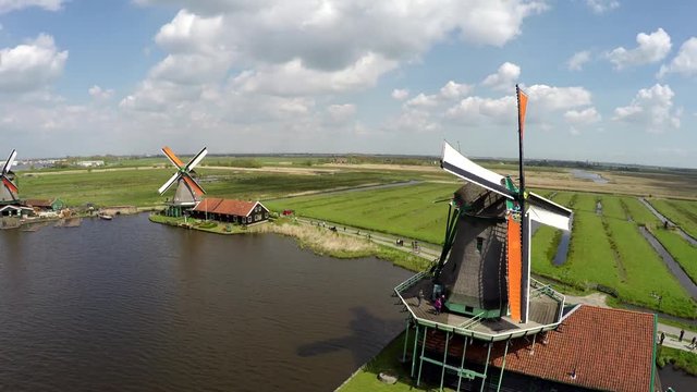Aerial Zaanse Schans moving past windmills showing mill blades turning by wind renewable energy great tourist attraction Netherlands Holland near Amsterdam beautiful drone footage bird-eye view 4k