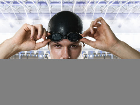 Male swimmer adjusting swimming goggles