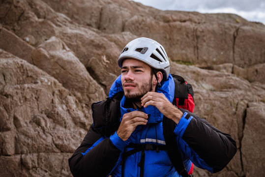 Young male climber on rock fastening helmet, The Lake District, Cumbria, UK
