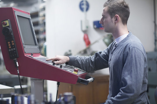 Young male technician using control panel in workshop