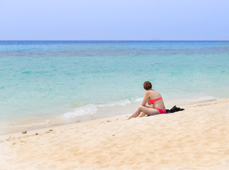 Fototapeta na wymiar woman sitting on the beach looking in the sea.