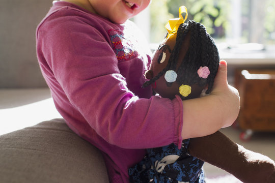 Cropped shot of baby girl in living room hugging rag doll