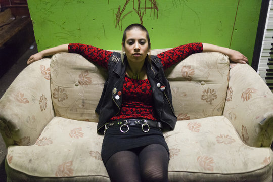 Portrait of punk girl, sitting on sofa