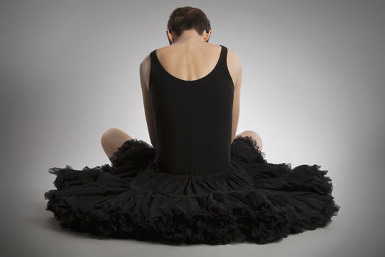 Rear view of woman sitting on floor wearing black tutu