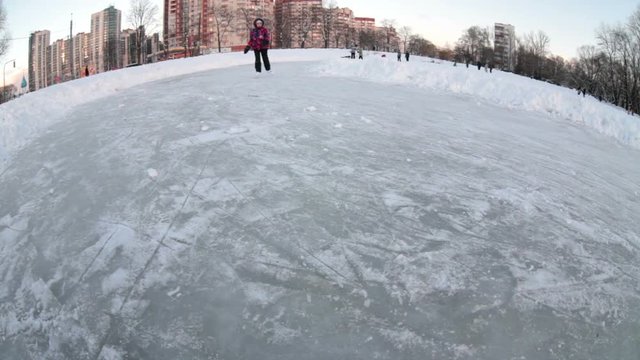 Pretty happy Caucasian girl skating on frozen ice of urban lake. Wide angle view. Sleeping district in Saint-Petersburg, Russia
