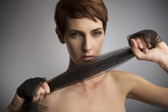 Studio portrait of woman pulling black silk scarf around hands