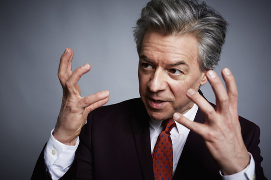Studio portrait of mature businessman with hands open in explanation