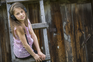 Fototapeta premium Cute little girl with headphones, portrait outdoors.