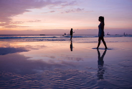Silhouetted young woman strolling on beach at sunset, Boracay Island, Visayas, Philippines