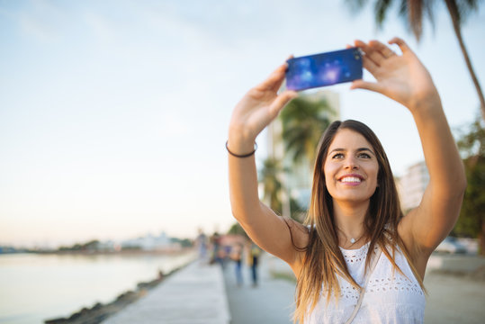 Young woman taking smartphone selfie on waterfront, Manila, Philippines