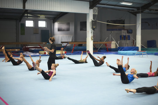 Gymnastics instructor overseeing class practising stretches
