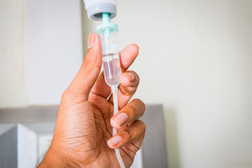 hand holding saline IV drip for patient in hospital room