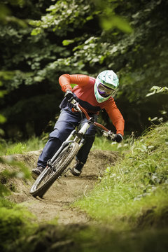 Young woman downhill mountain biking in forest