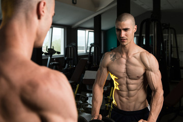 Fototapeta na wymiar Man Flexing Muscles In Front Of A Mirror