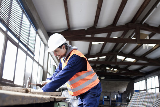Factory worker hammering on workbench in concrete reinforcement factory