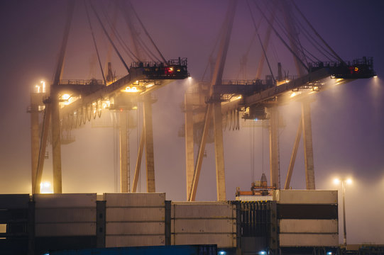 Misty view of harbor cranes and stacked cargo containers at night, Seattle, Washington, USA