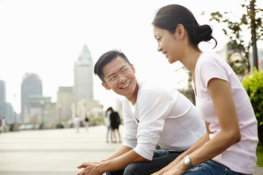 Tourist couple sitting on wall, The Bund, Shanghai, China