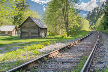 Fototapeta na wymiar Small old hut alongside train tracks leading into distance