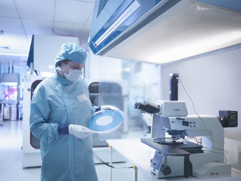 Electronics worker in clean room with silicon wafer