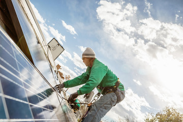 Construction crew member installing a solar panel on a house