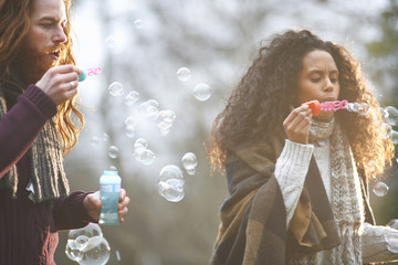 Couple blowing soap bubbles in countryside