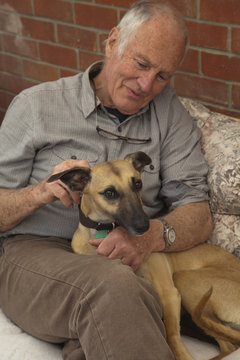 Senior man, sitting, stroking pet dog
