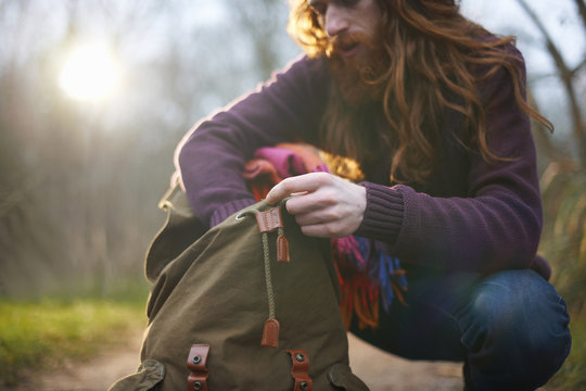 Man kneeling, rummaging in backpack