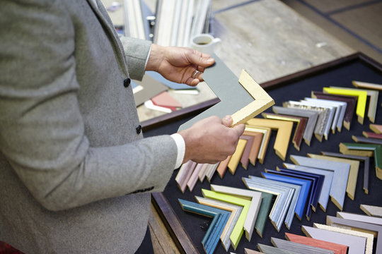 Cropped shot of framer selecting frame in picture framers workshop