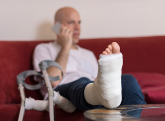 Young man with a broken ankle and a leg cast