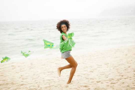 Young woman playing with string of flags on beach, Rio de Janeiro, Brazil