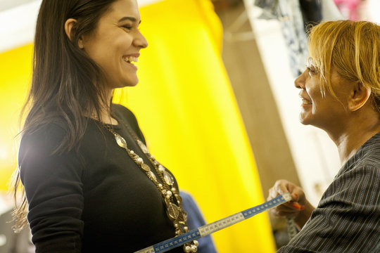 Seamstress measuring client in sewing shop