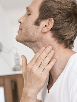 Close up of man in bathroom applying moisturizer to neck
