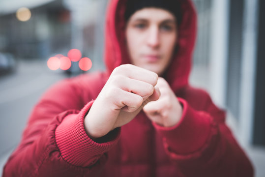 Close up of young mans posing with clenched fists on city street