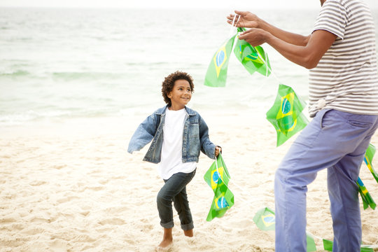 Family playing with string of flags on beach, Rio de Janeiro, Brazil