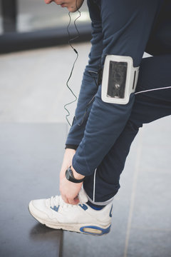 Cropped shot of young male runner fastening trainer lace