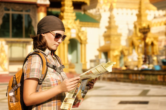 Woman traveling with backpack and looks at map temple Buddhist Shwedagon