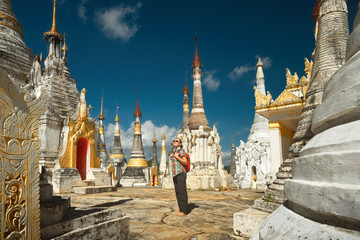 Woman traveling with backpack and looks at stupas Buddhist temple