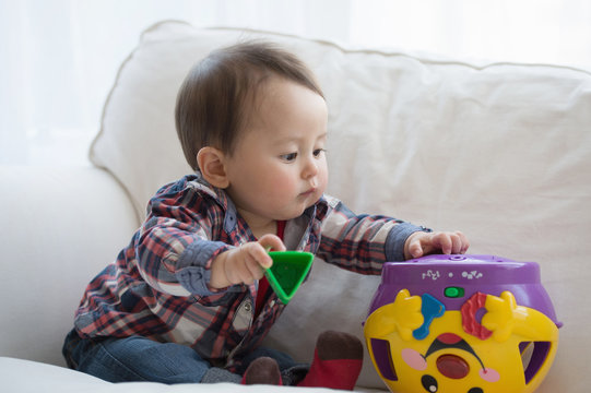 Baby boy playing with shape sorter toy