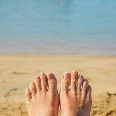 Female feet in the sand against beach and sea