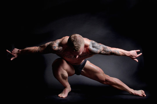 Muscular young man stretching with arms out