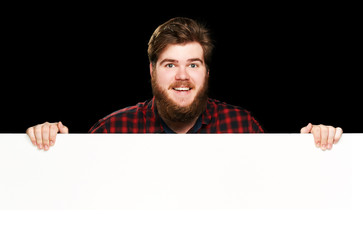 Happy guy smiles at the camera peeking behind wall 